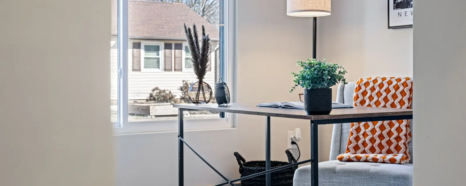 Small home office with a desk, lamp and armchair beside a bright window