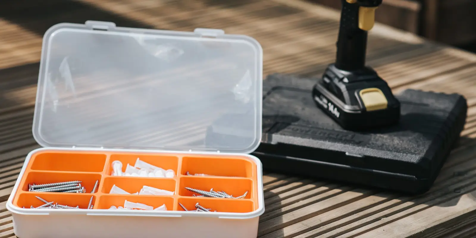 Unbranded cordless drill on its case next to a box of screws and wall plugs